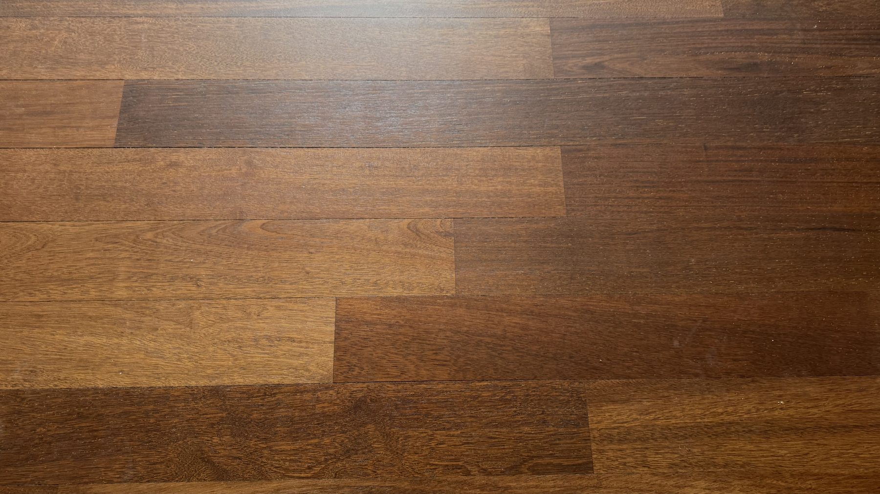 Après : Gros plan d'un parquet merbau : à gauche rayé et terni, à droite poncé et verni