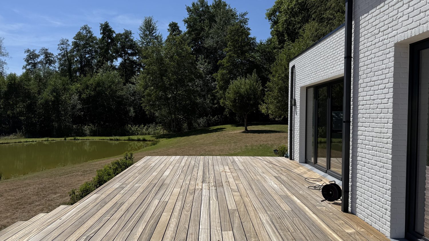 Terrasse en ipe le long de la maison, étang en arrière-plan