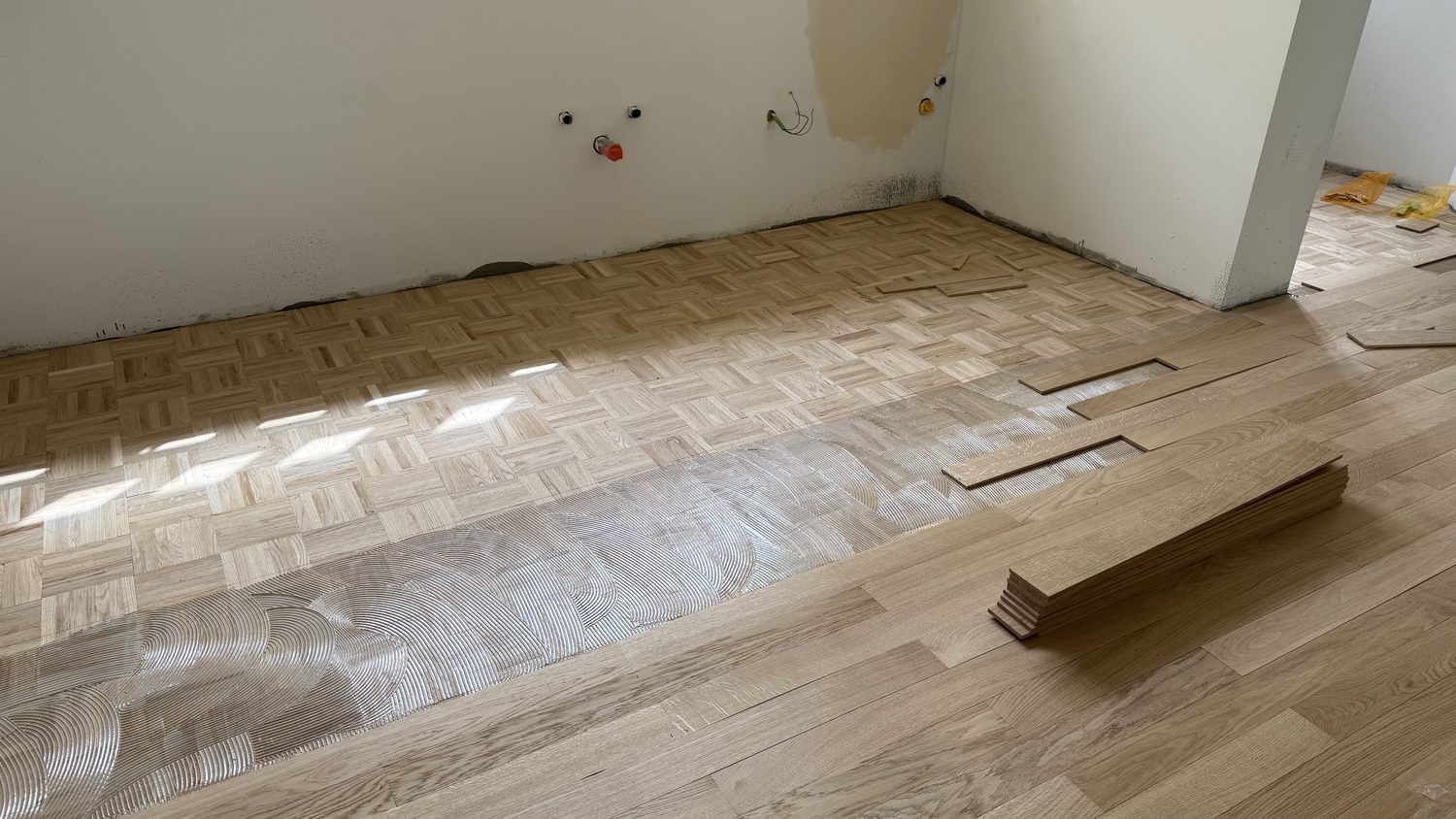 Chantier de pose : ancien parquet, colle peignée et lames de chêne neuves