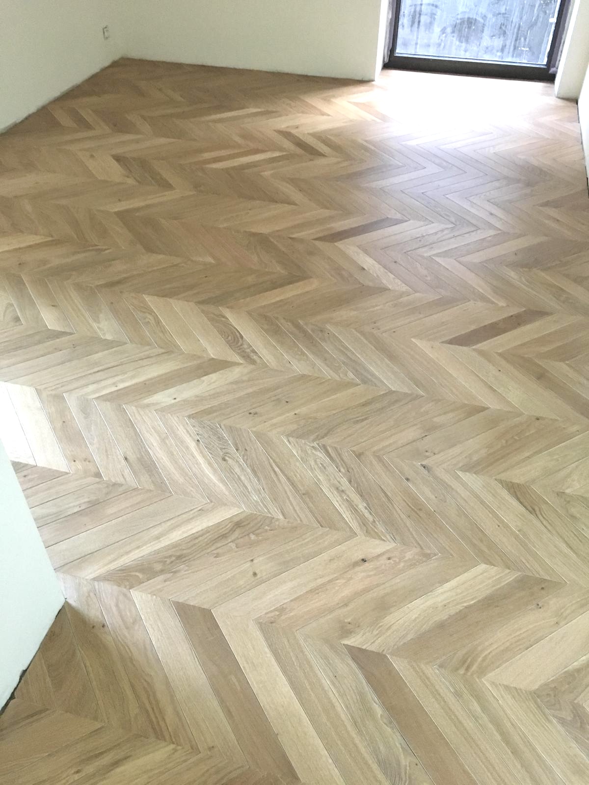 Parquet chêne clair posé en point de Hongrie dans une pièce en travaux, motif continu en V